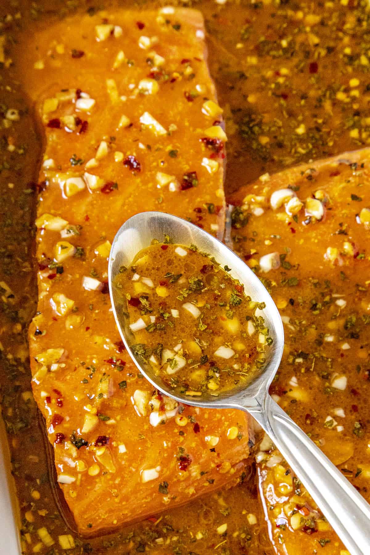 Spooning some spicy salmon marinade over salmon fillets