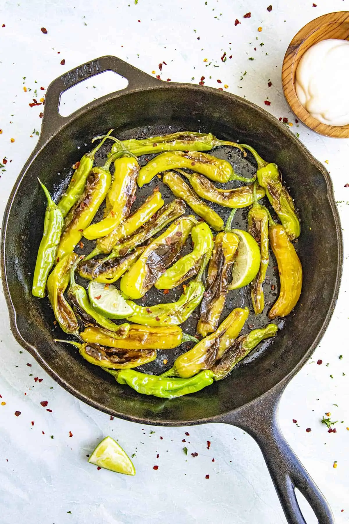 Hot Blistered Shishito Peppers in a pan with salt and lime