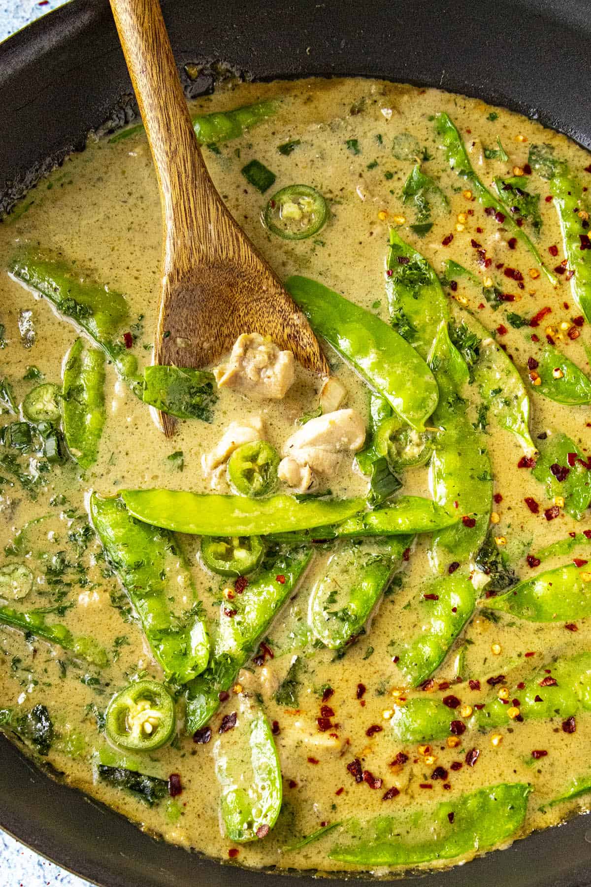 Scooping spicy green curry from the pan