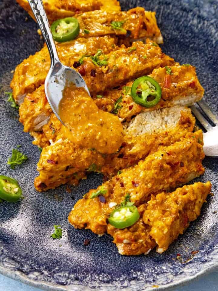 Spooning extra harissa sauce onto my Baked Harissa Chicken Breast