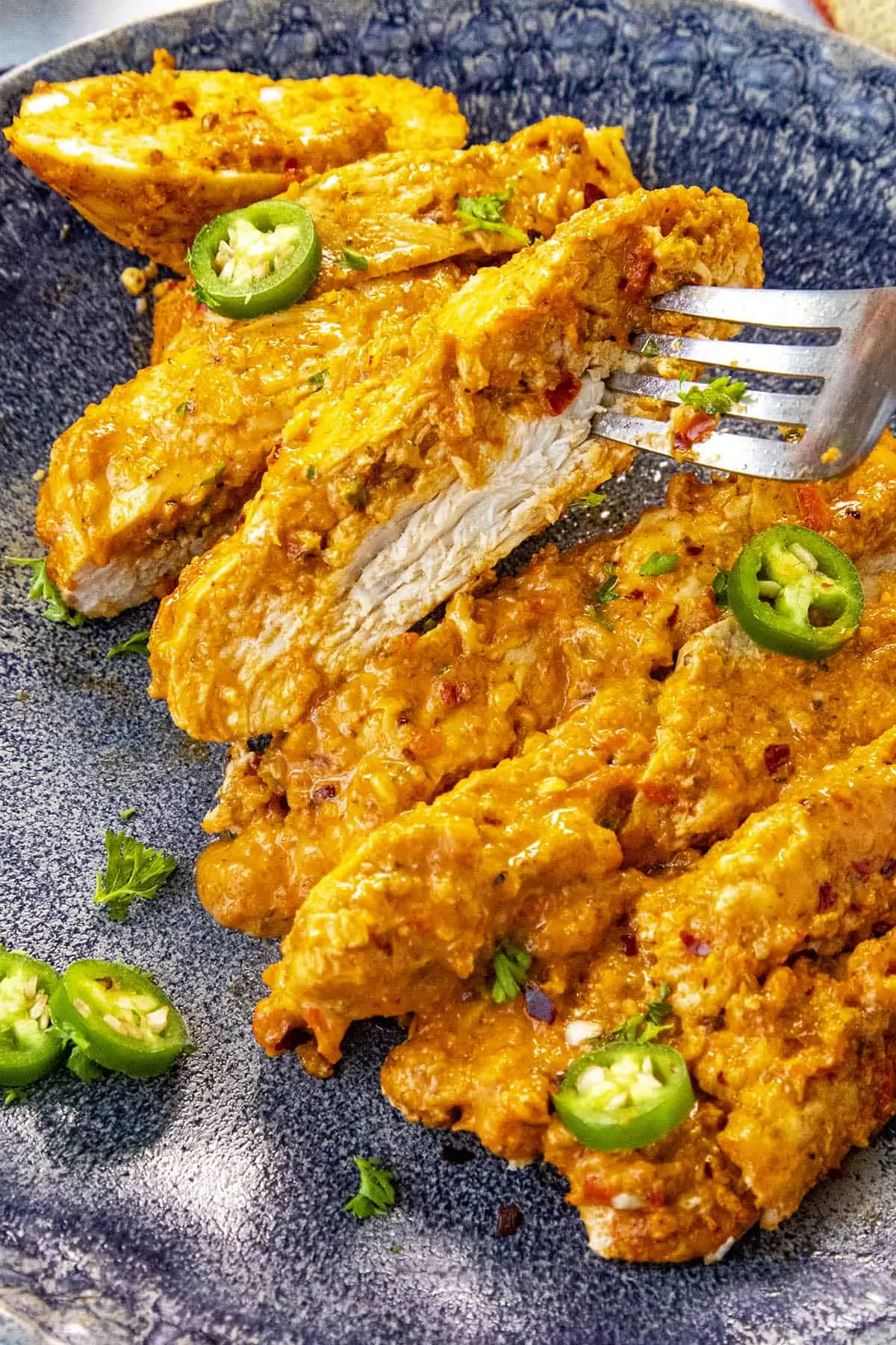 Taking a slice of Baked Harissa Chicken Breast from a plate