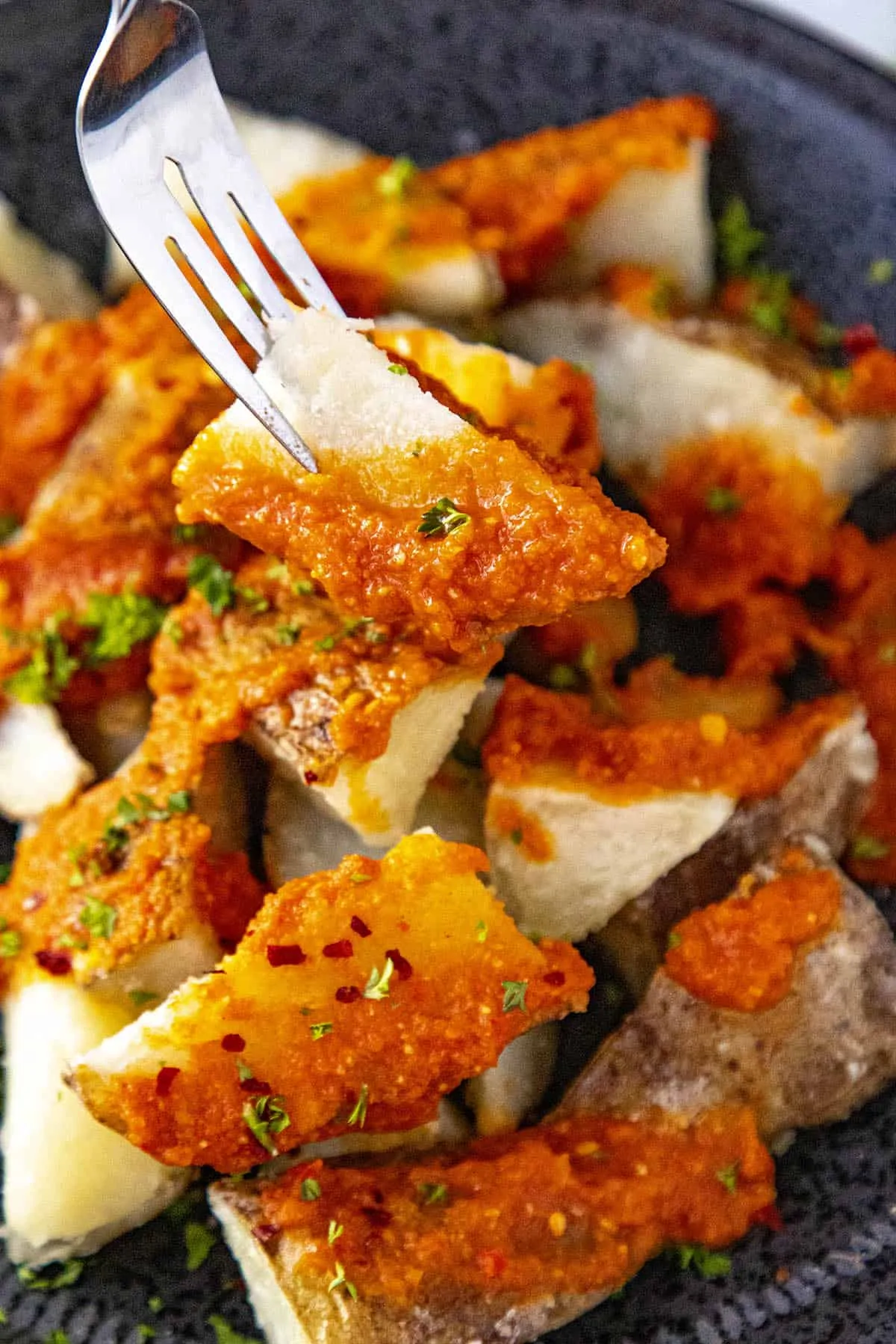 Patatas Bravas on a fork, covered with spicy bravas sauce