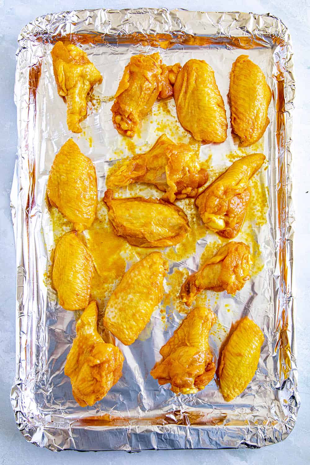 Seasoned chicken wings on a baking sheet, ready for the smoker