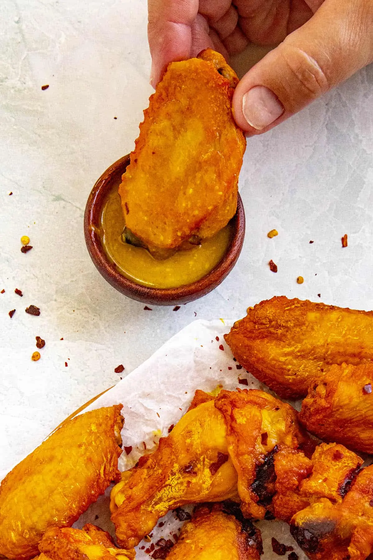 Dipping a smoked chicken wing into wing sauce