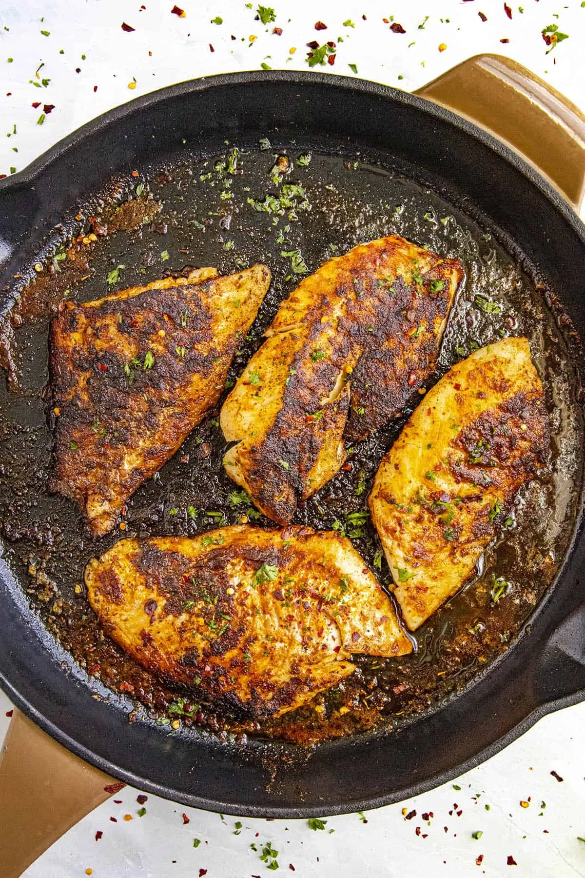 Spicy Blackened Fish in a pan with lots of seasoning