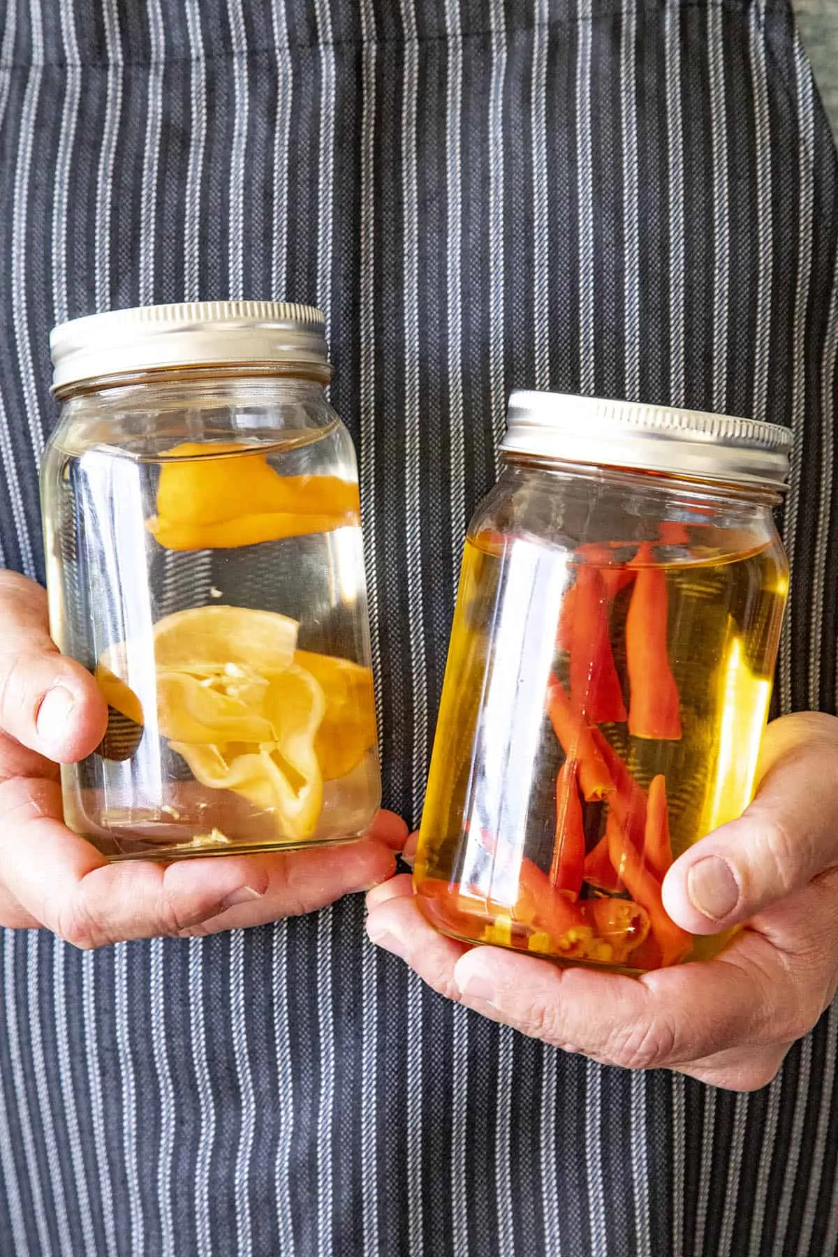 Mike holding 2 jars of chili infused alcohol