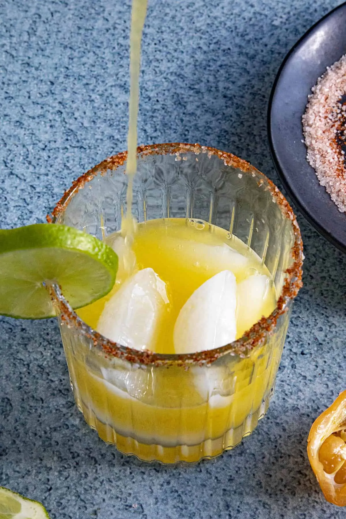 Pouring some Spicy Mango Margarita into a glass with ice