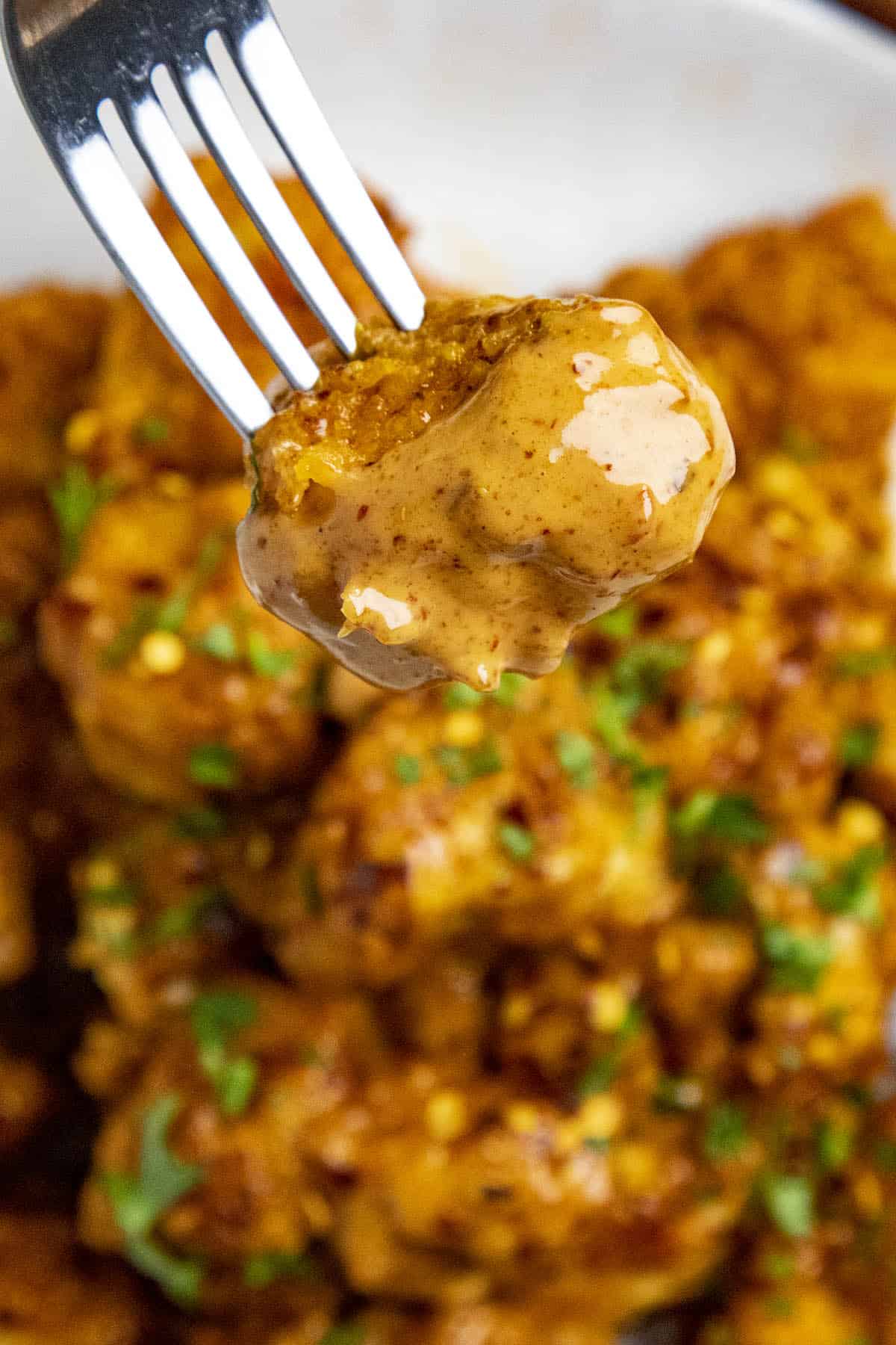 A piece of bang bang chicken dipped into bang bang sauce