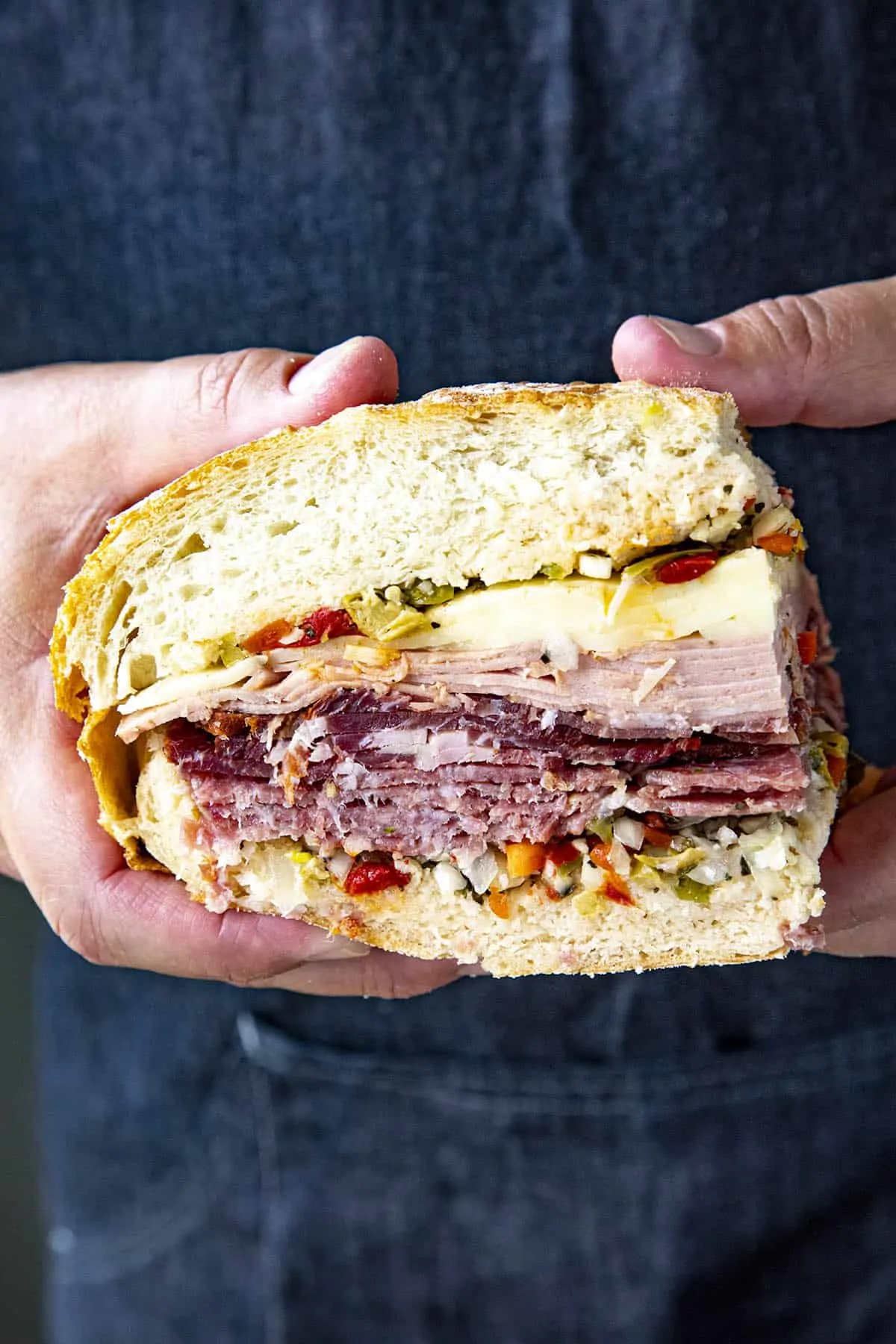 Mike holding a slice of a Muffaletta sandwich