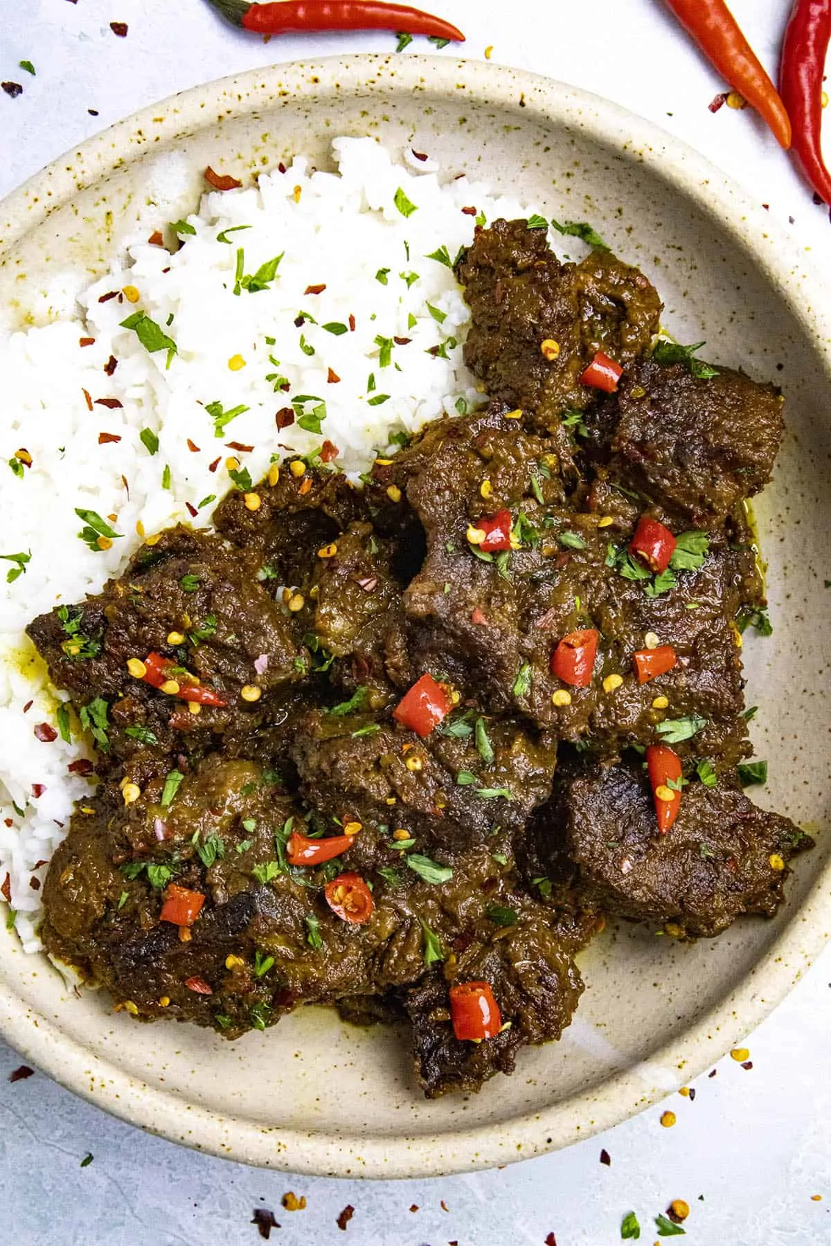 Beef Rendang in a bowl with sliced chili peppers as garnish