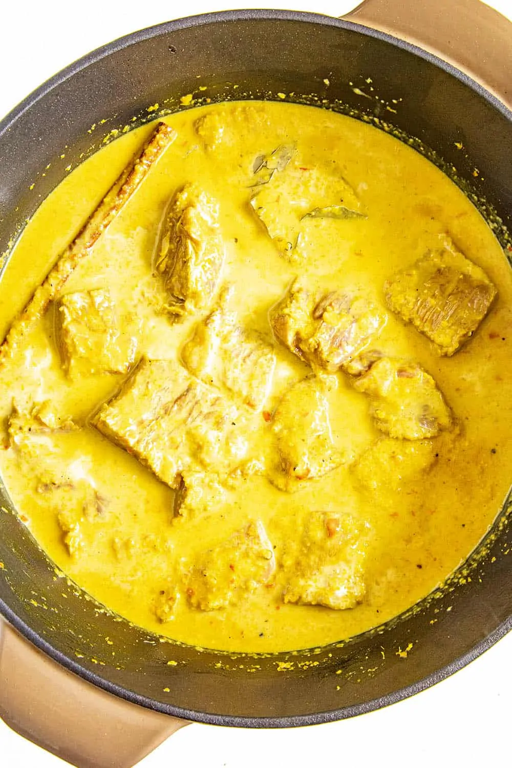 Adding the coconut milk to the pot of rendang