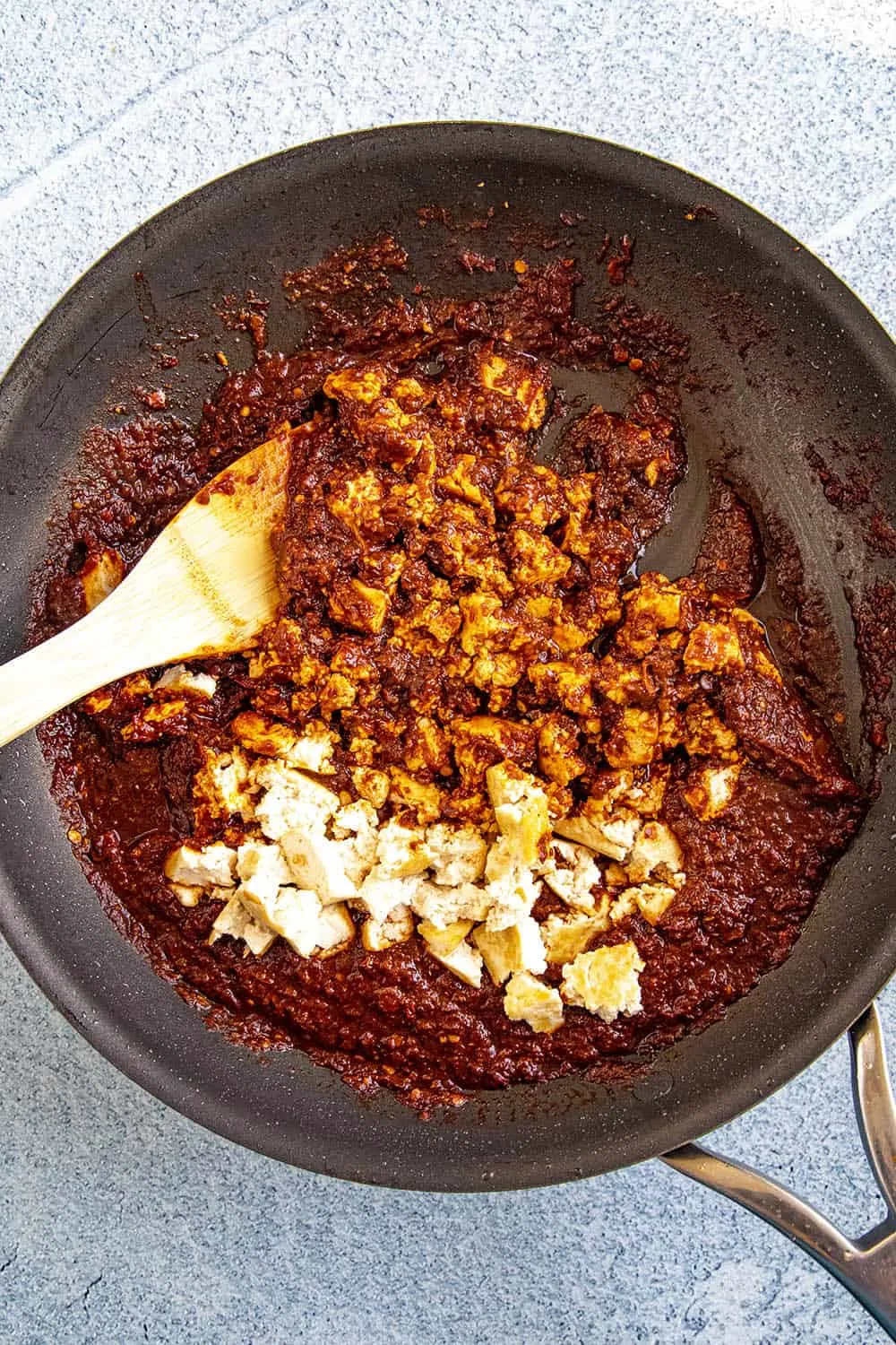 Stirring fried tofu into our spicy chipotle sofritas sauce