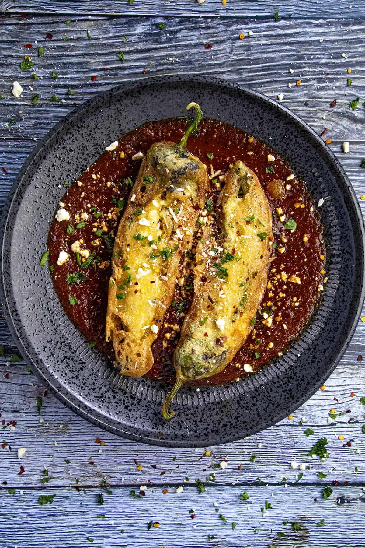 Two Chiles Rellenos on a plate with salsa roja (red sauce)