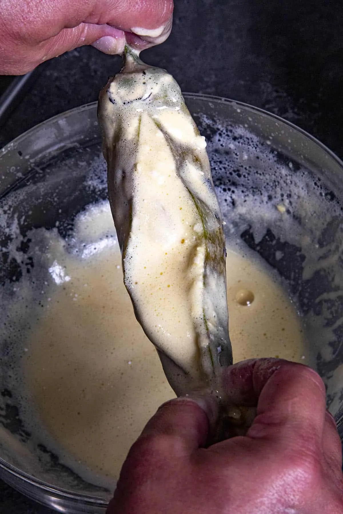 dipping a stuffed pepper in light batter