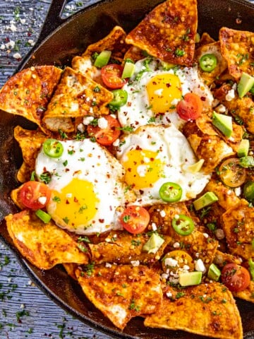 Mike serving up A pan full of Chilaquiles Rojos with fried eggs on top