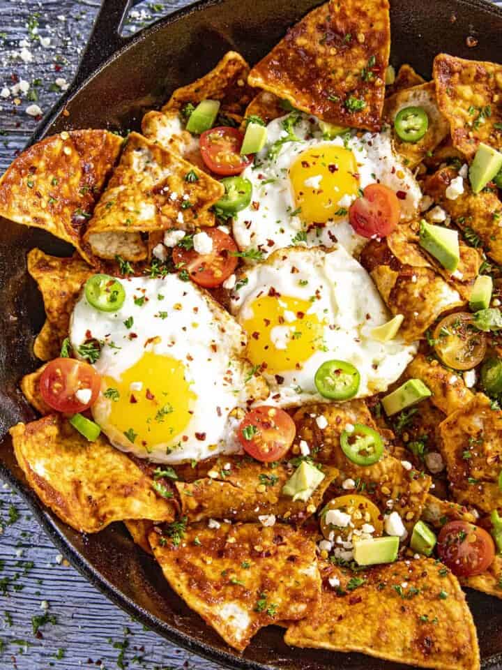 Mike serving up A pan full of Chilaquiles Rojos with fried eggs on top