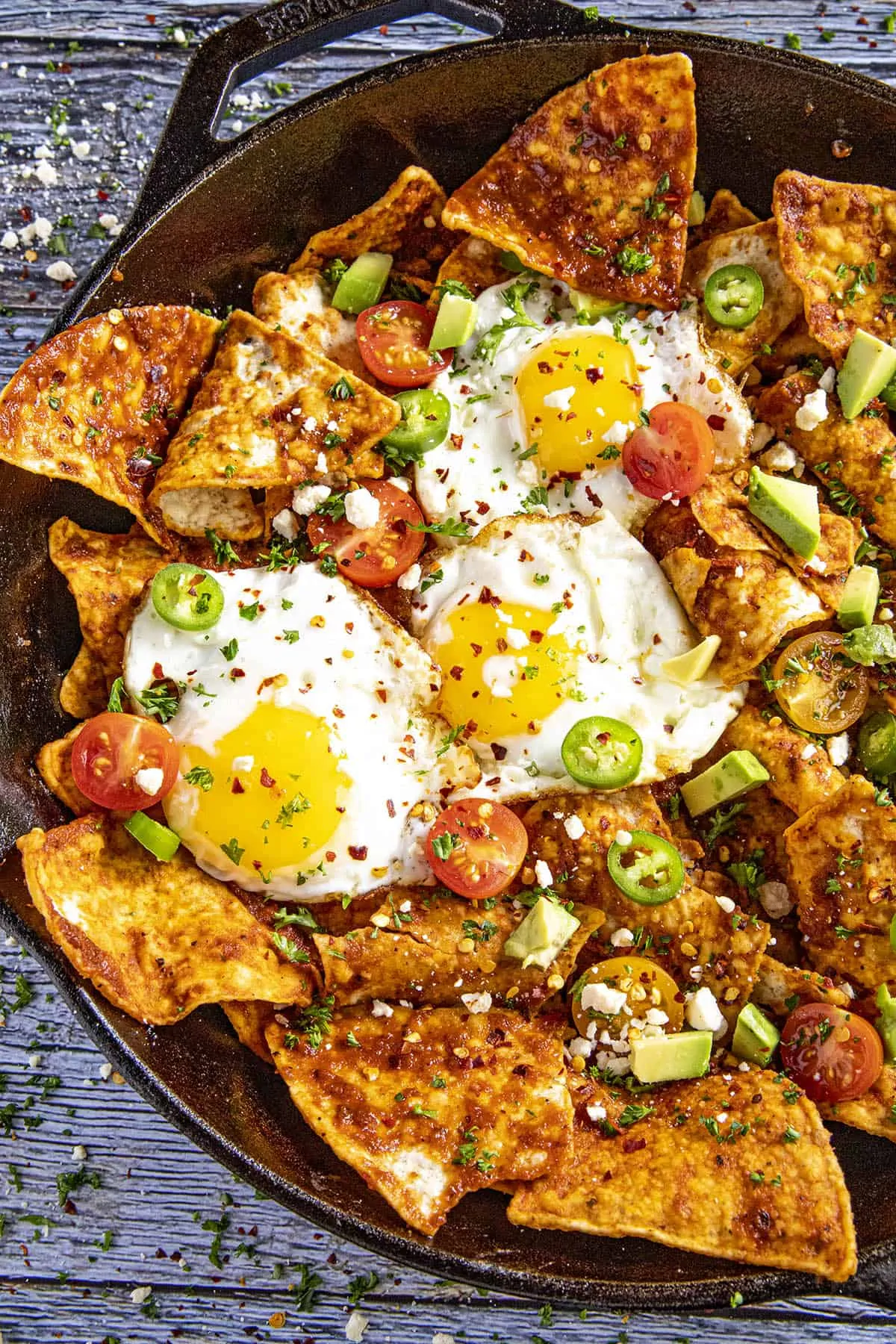 Mike serving up A pan full of Chilaquiles Rojos with fried eggs on top.