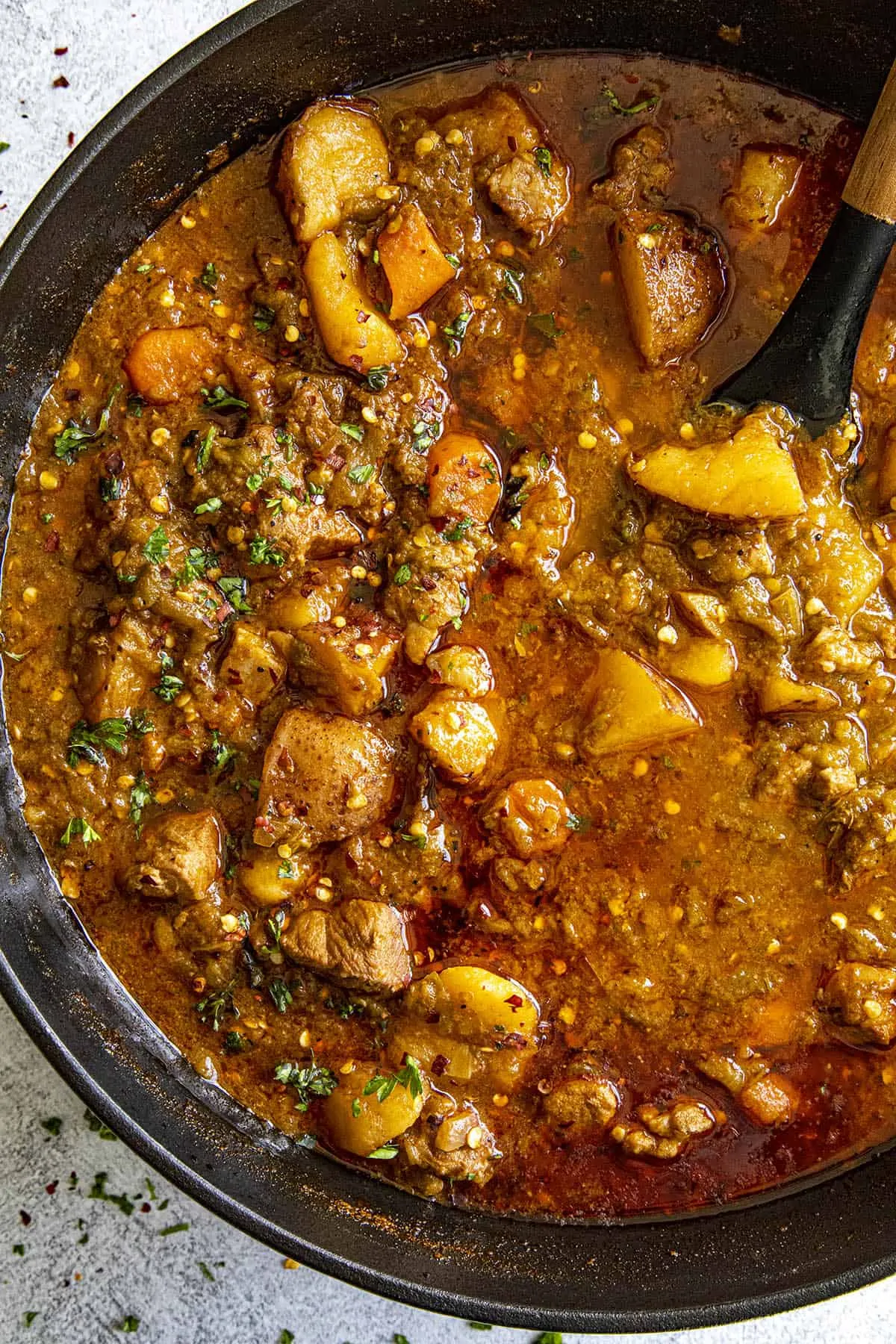 Stirring Green Chili Stew in a pot with a spoon.