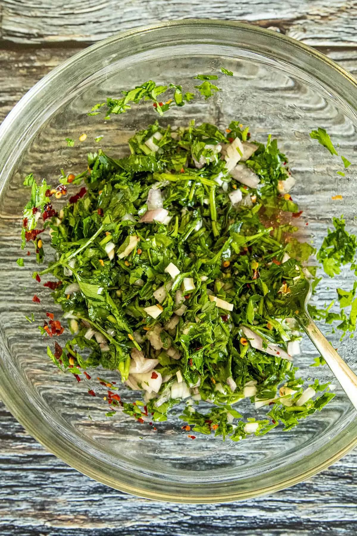 Mixing Chimichurri sauce in a bowl.