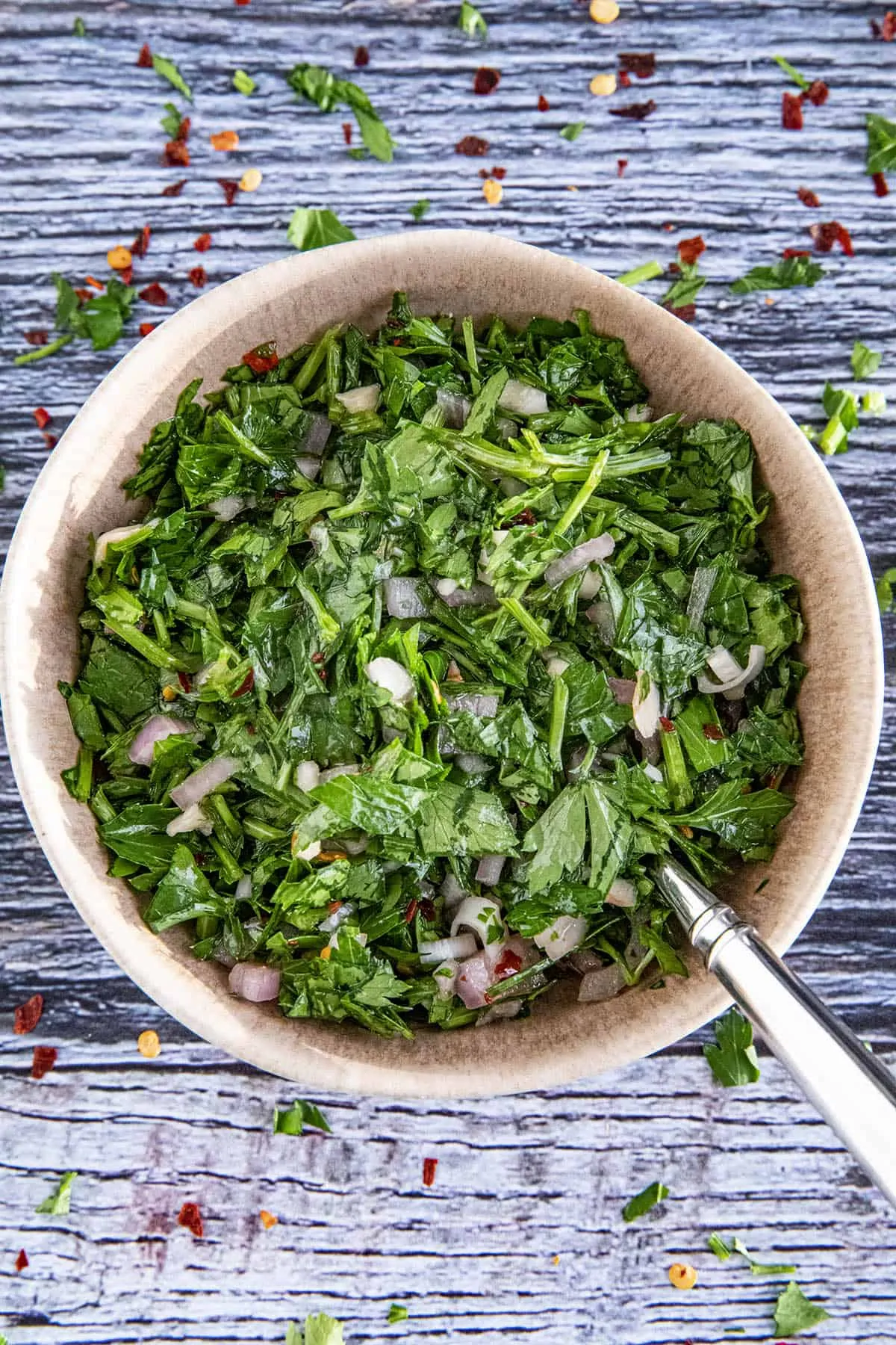 Chimichurri served in a big bowl with a spoon inside the bowl.