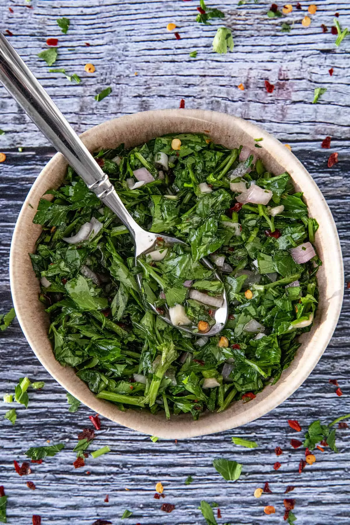 Chimichurri in a bowl with a spoon, ready to serve.