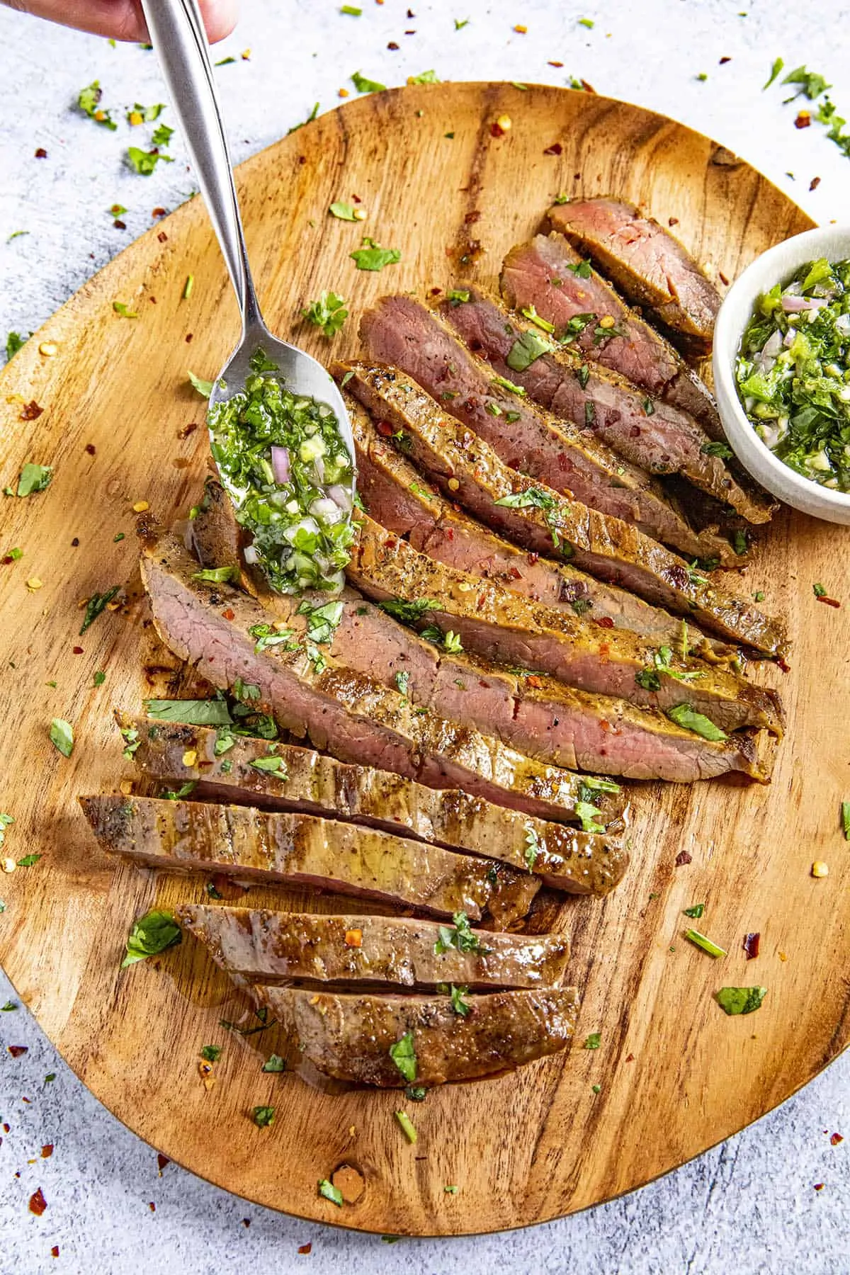 Mike spooning Chimichurri onto a sliced flank steak.