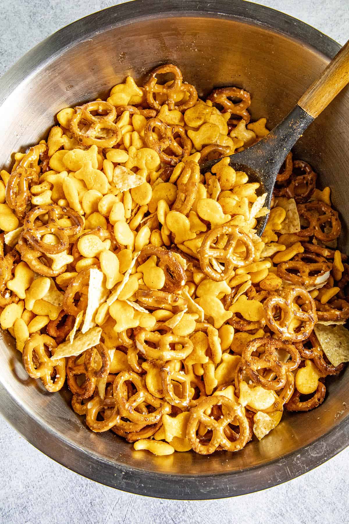 Mixing up my Homemade Spicy Snack Mix in a bowl with seasonings.