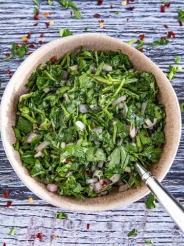 Chimichurri served in a big bowl with a spoon inside the bowl.