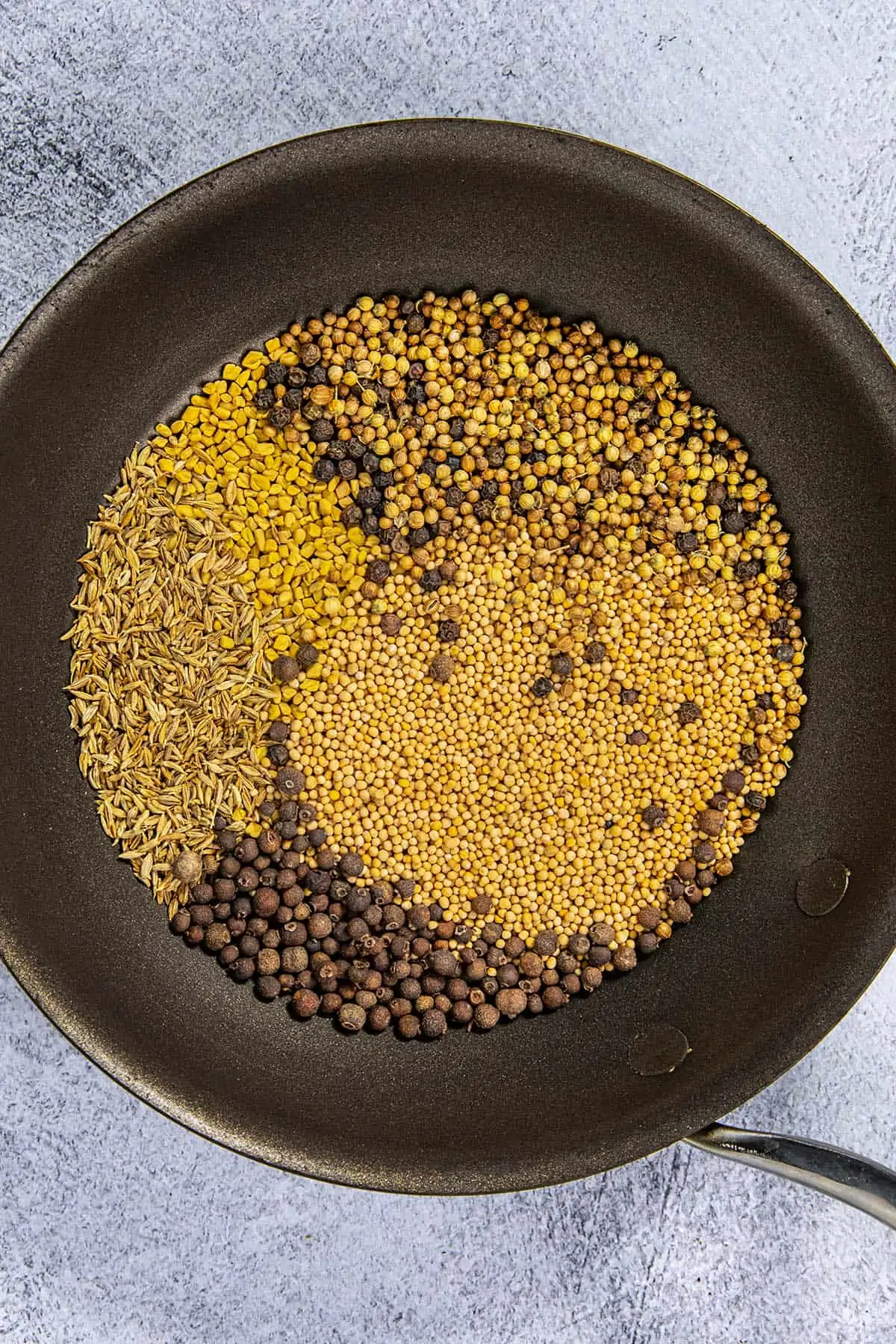 Toasting the seeds and dried berries in a pan to make Jamaican Curry Powder.