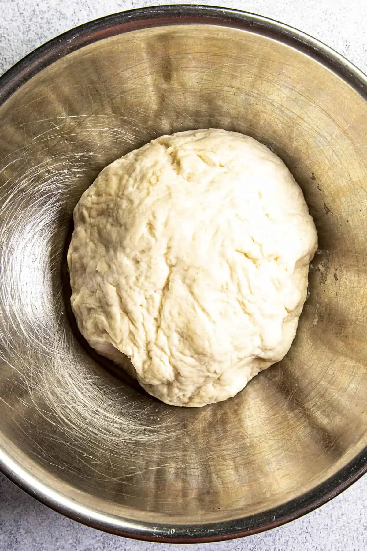 A mixed pizza dough ball, starting to rise