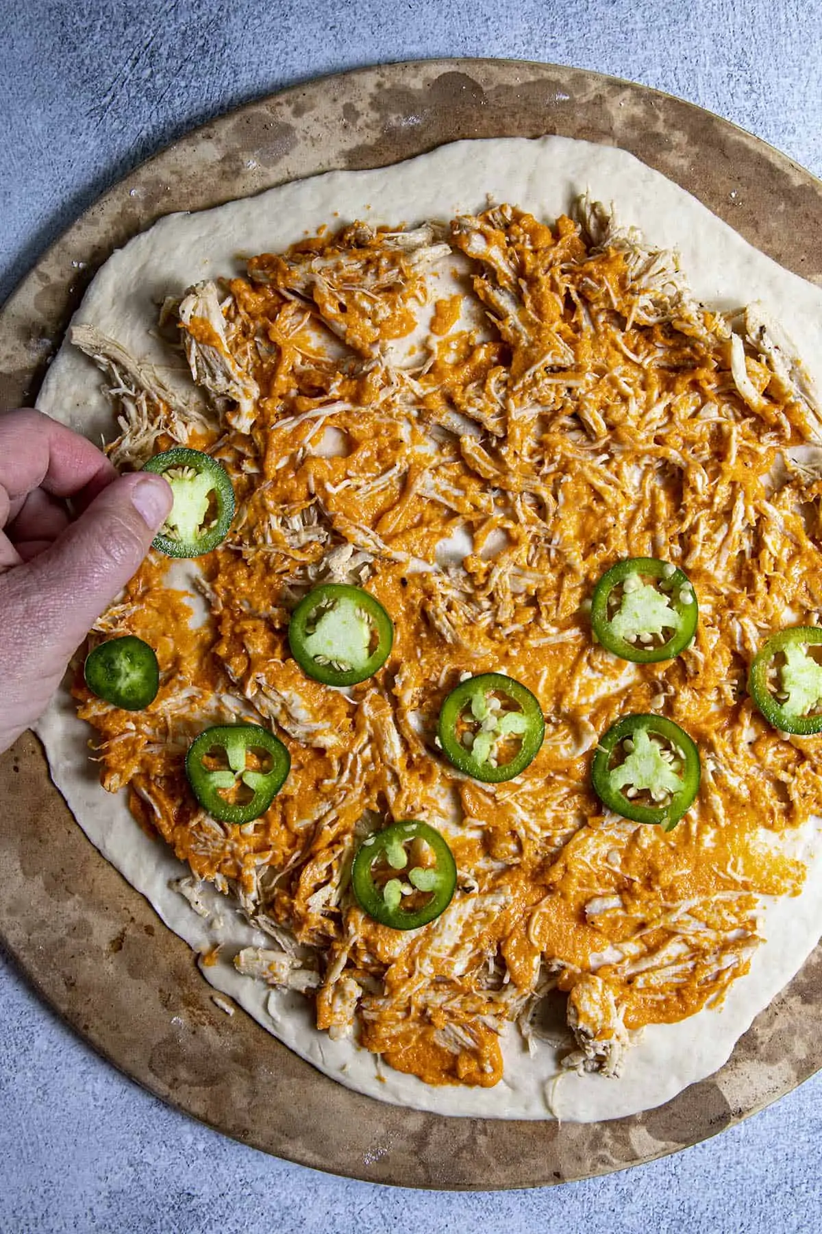 Adding peppers to the Buffalo Chicken Pizza