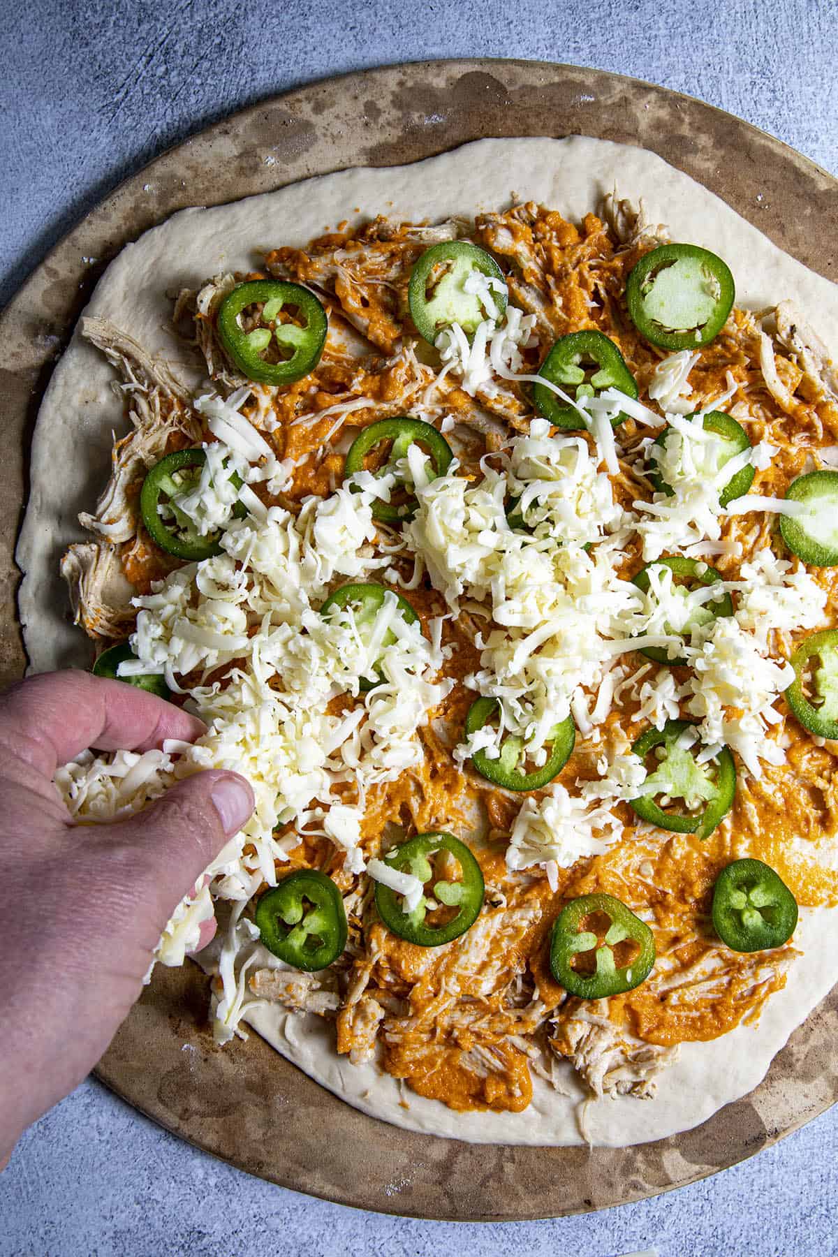 Adding cheese to the Buffalo Chicken Pizza