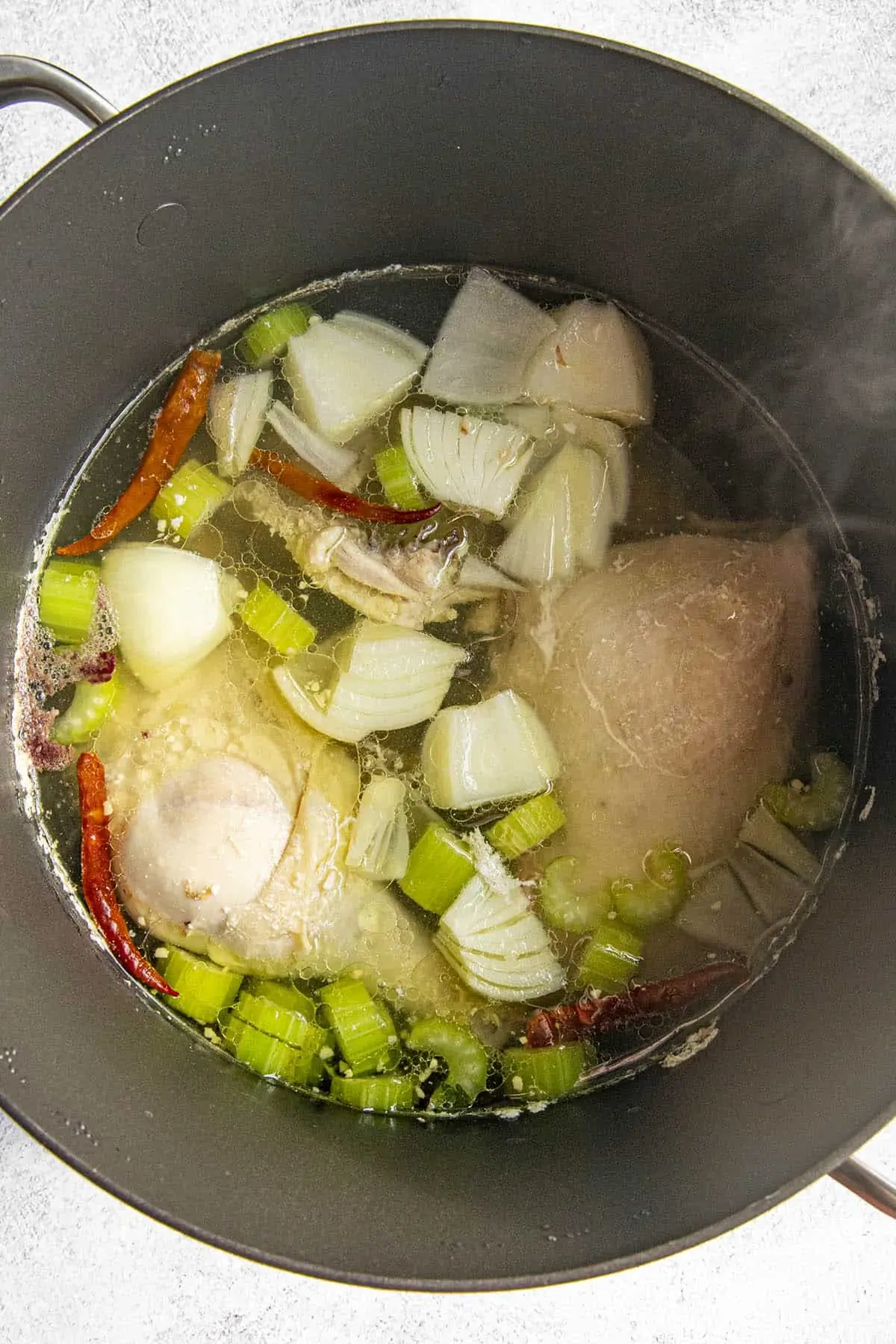 Simmering chicken and vegetables in a pot to make caldo de pollo