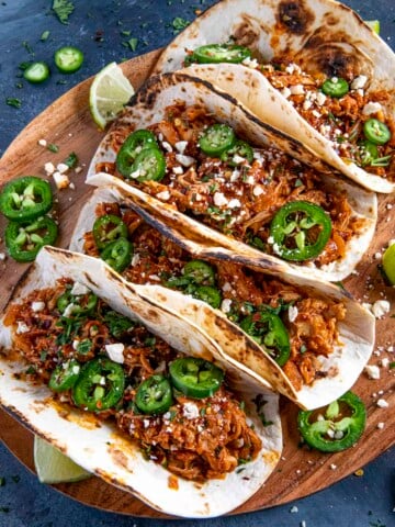 Chicken Tinga Tacos served on a wooden board