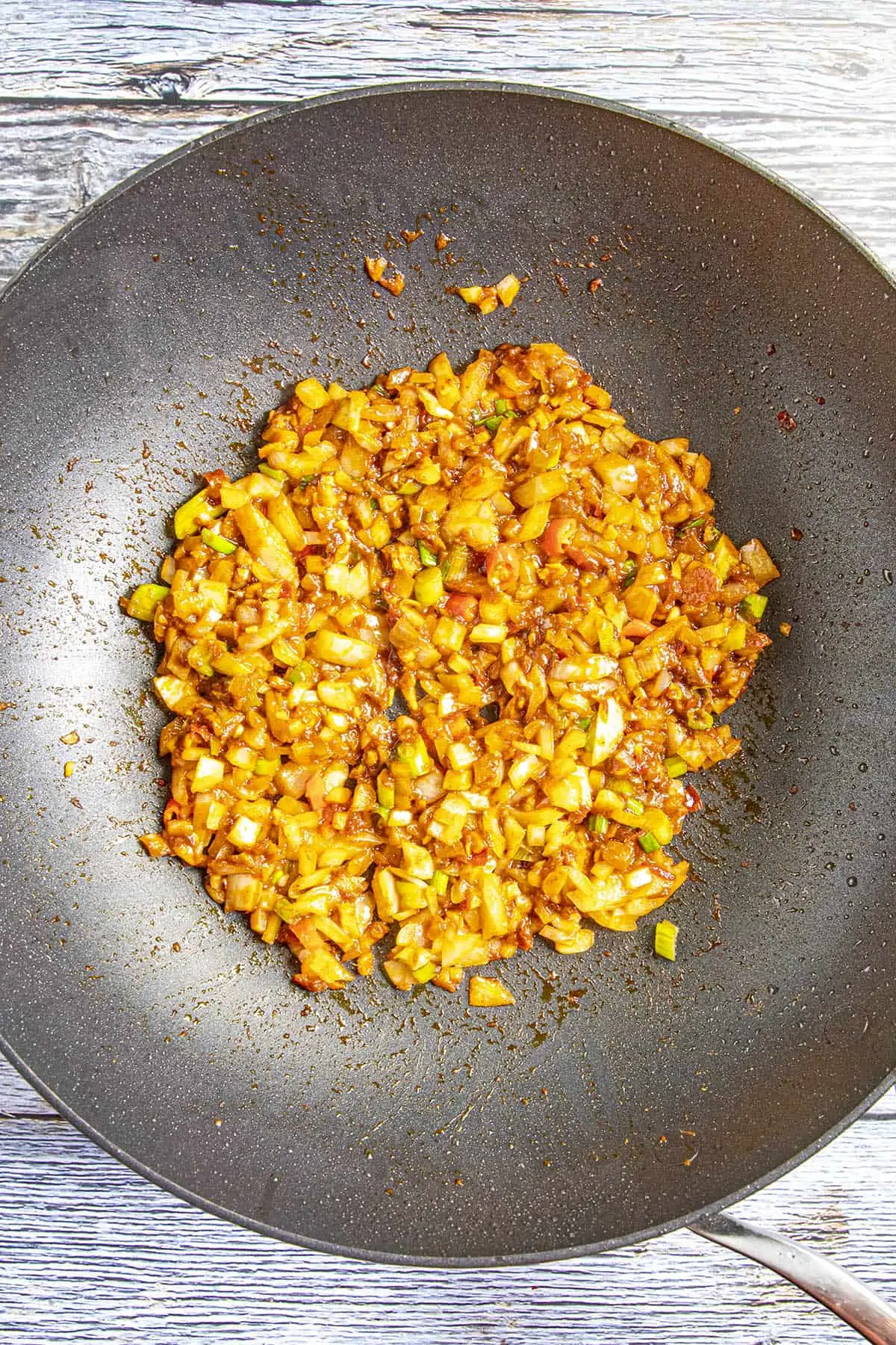 Adding the vegetables and chili paste together in the pan.