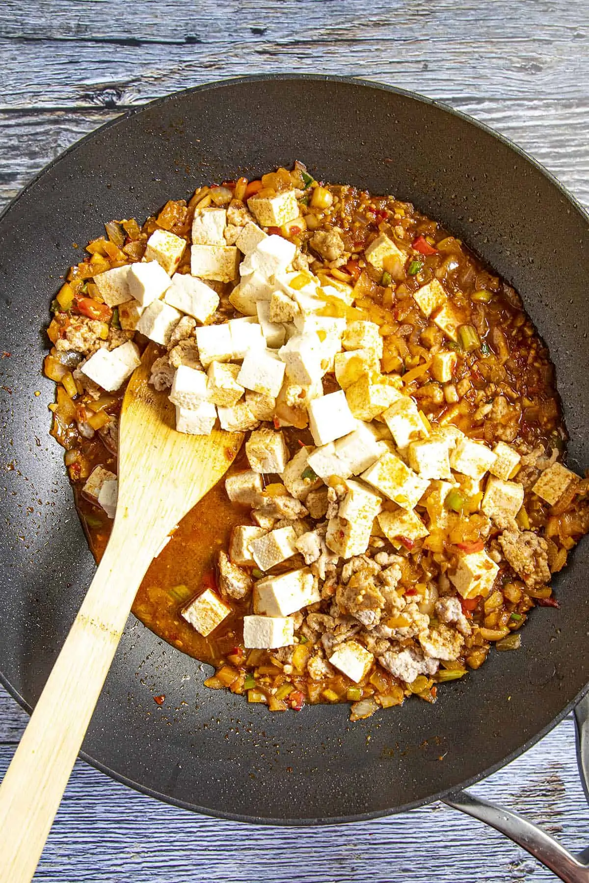 Stirring the tofu into my pan of Mapo Tofu.