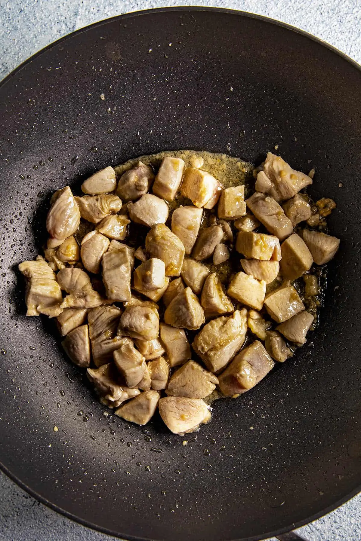 Cooking chicken in a wok to make Bourbon Chicken