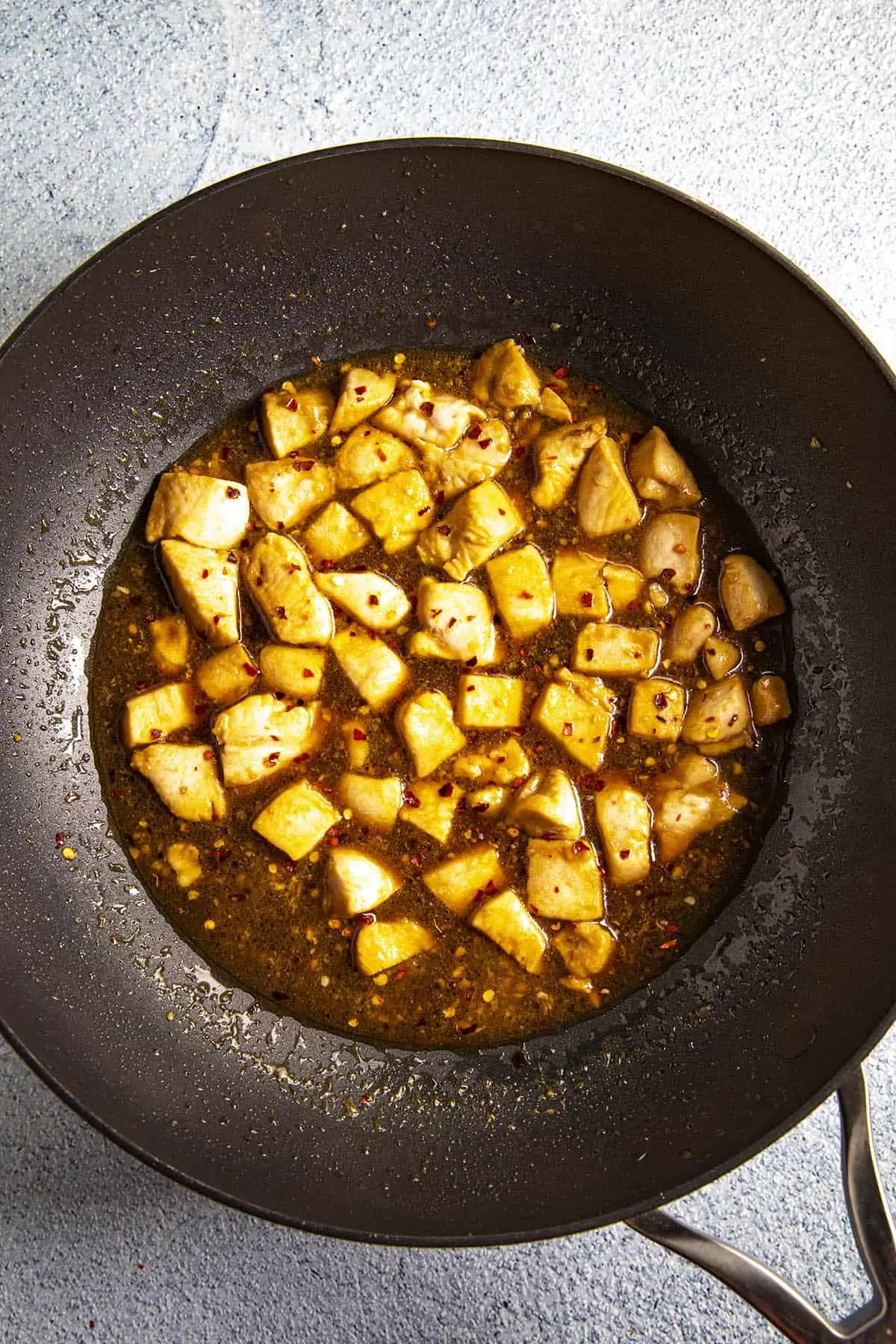 Simmering the Bourbon Chicken in a wok with the sauce