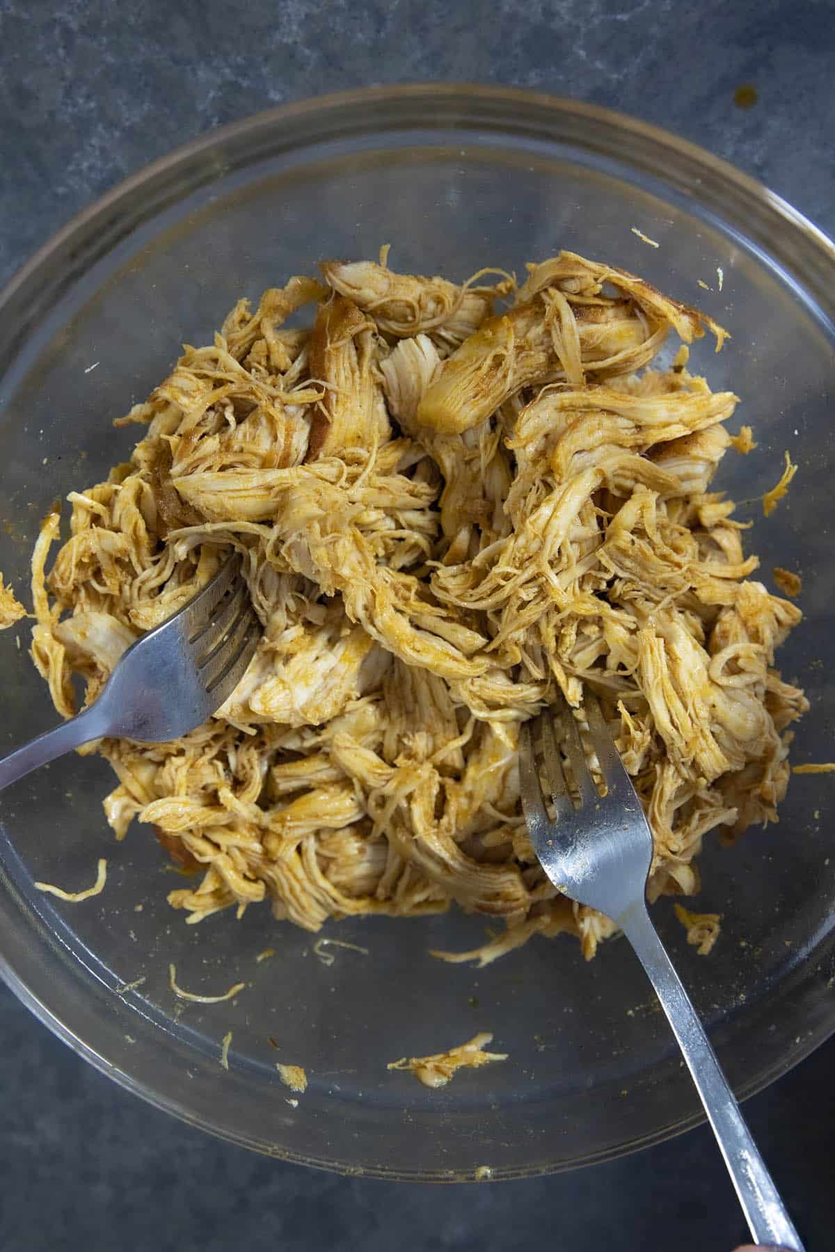 Shredding cooked chicken in a bowl