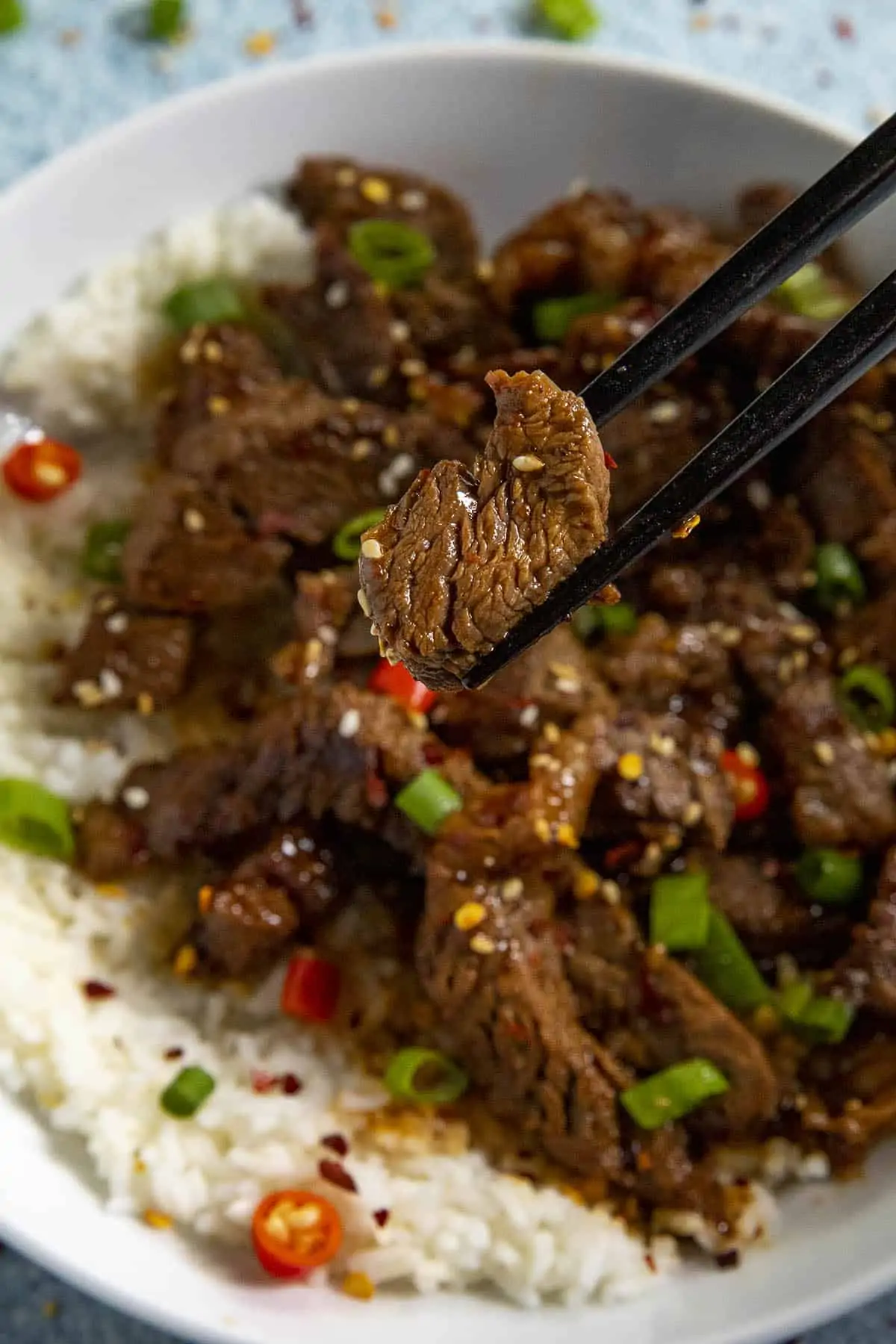 Chopsticks grabbing a slice of bulgogi from a bowl