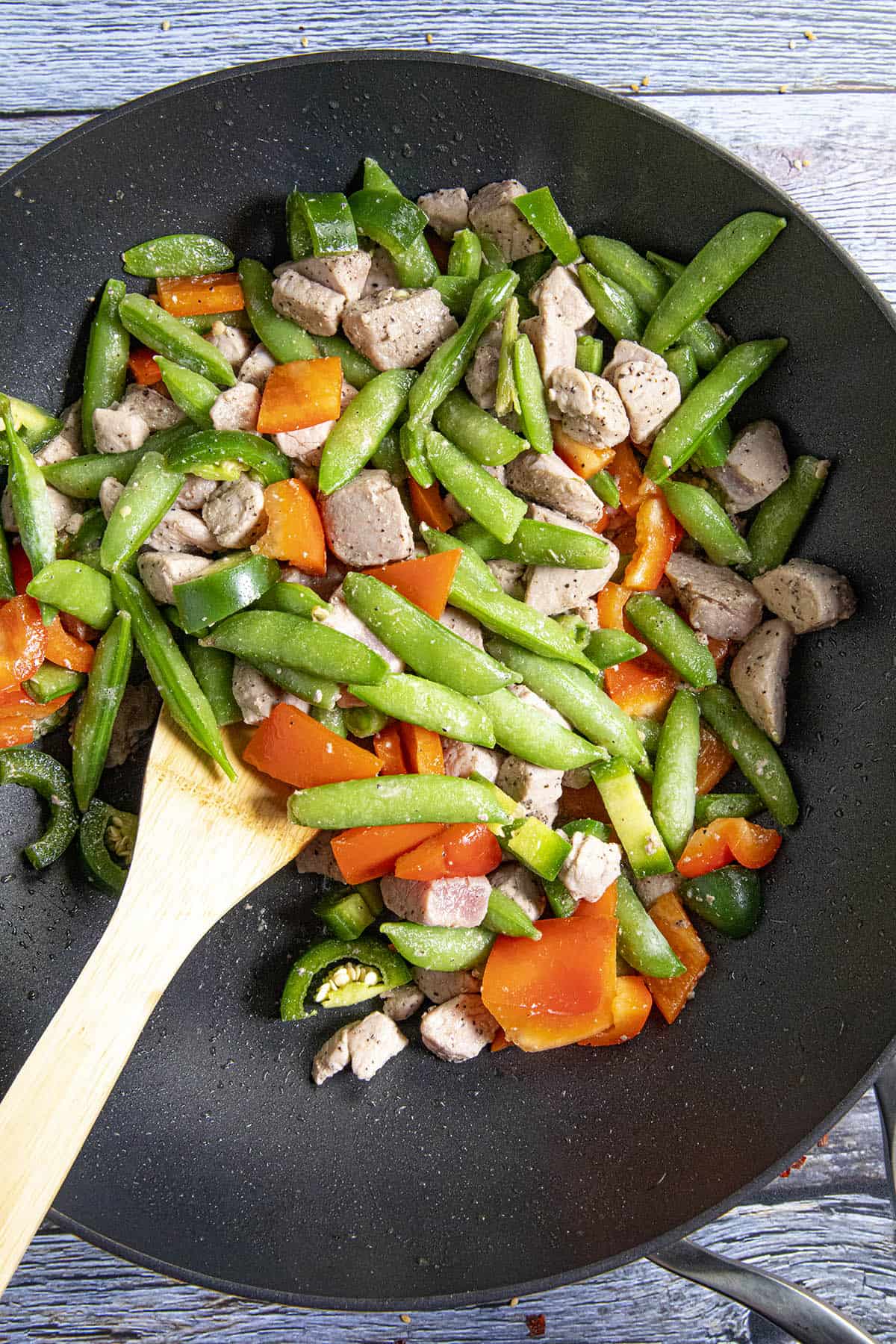 Stir frying the vegetables in a hot wok with the pork.