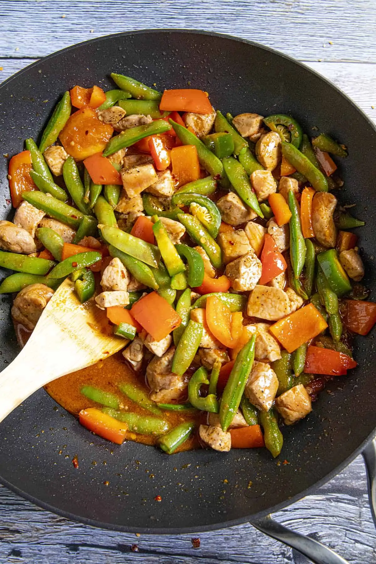 Stirring the stir fry sauce into the pan with the pork and vegetables