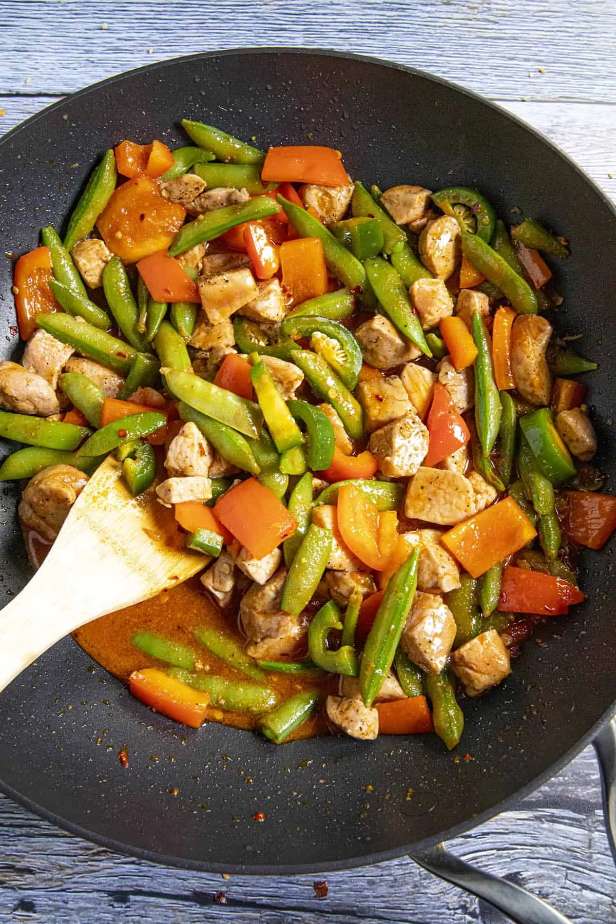 Stirring the stir fry sauce into the pan with the pork and vegetables.