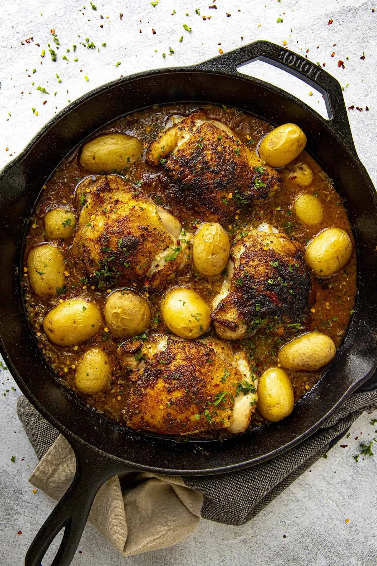 Baked Chicken Thighs in a hot pan with potatoes and lots of Cajun seasonings