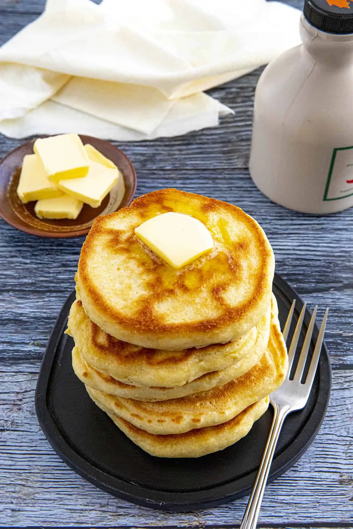 A stack of Johnny Cakes on a serving plate with melted butter