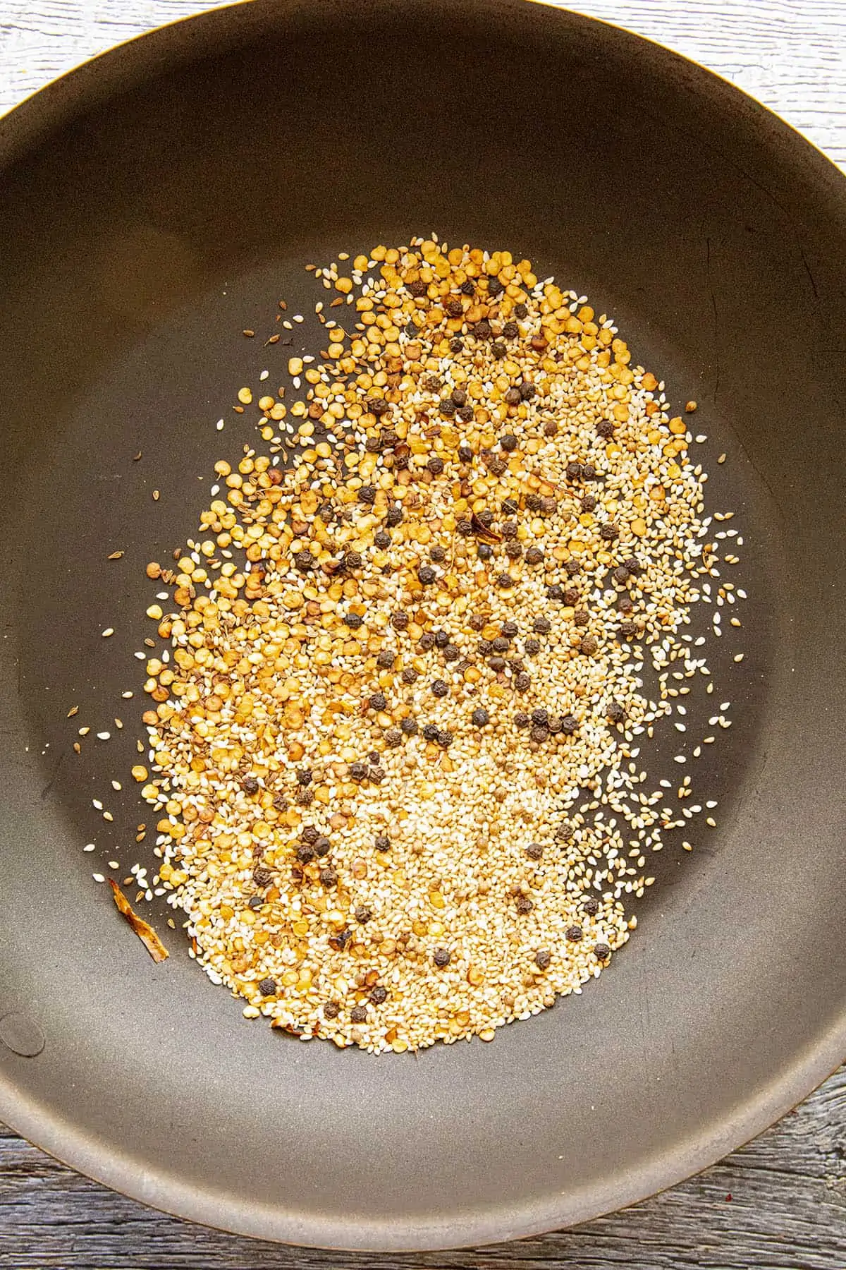 Toasting the seeds and seasonings in a hot pan.