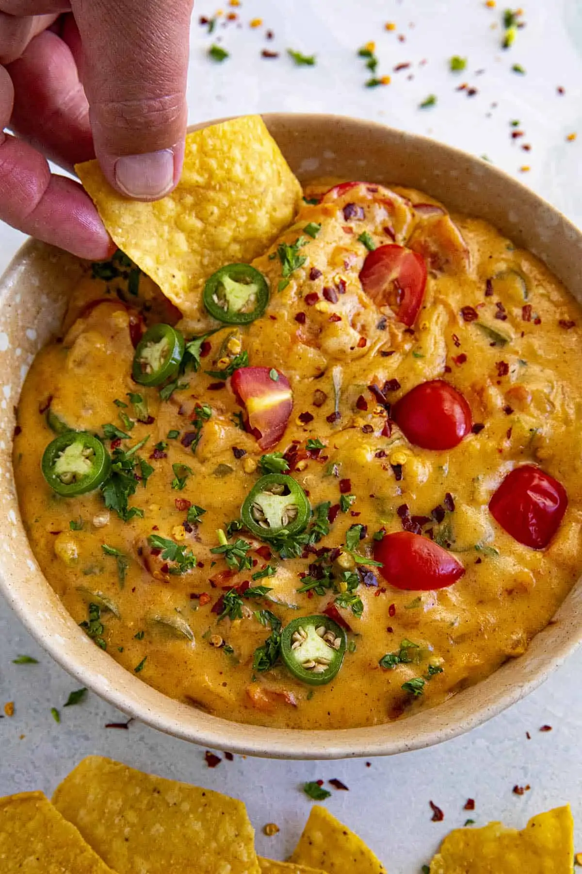 Mike taking a scoop of queso dip with a tortilla chip.