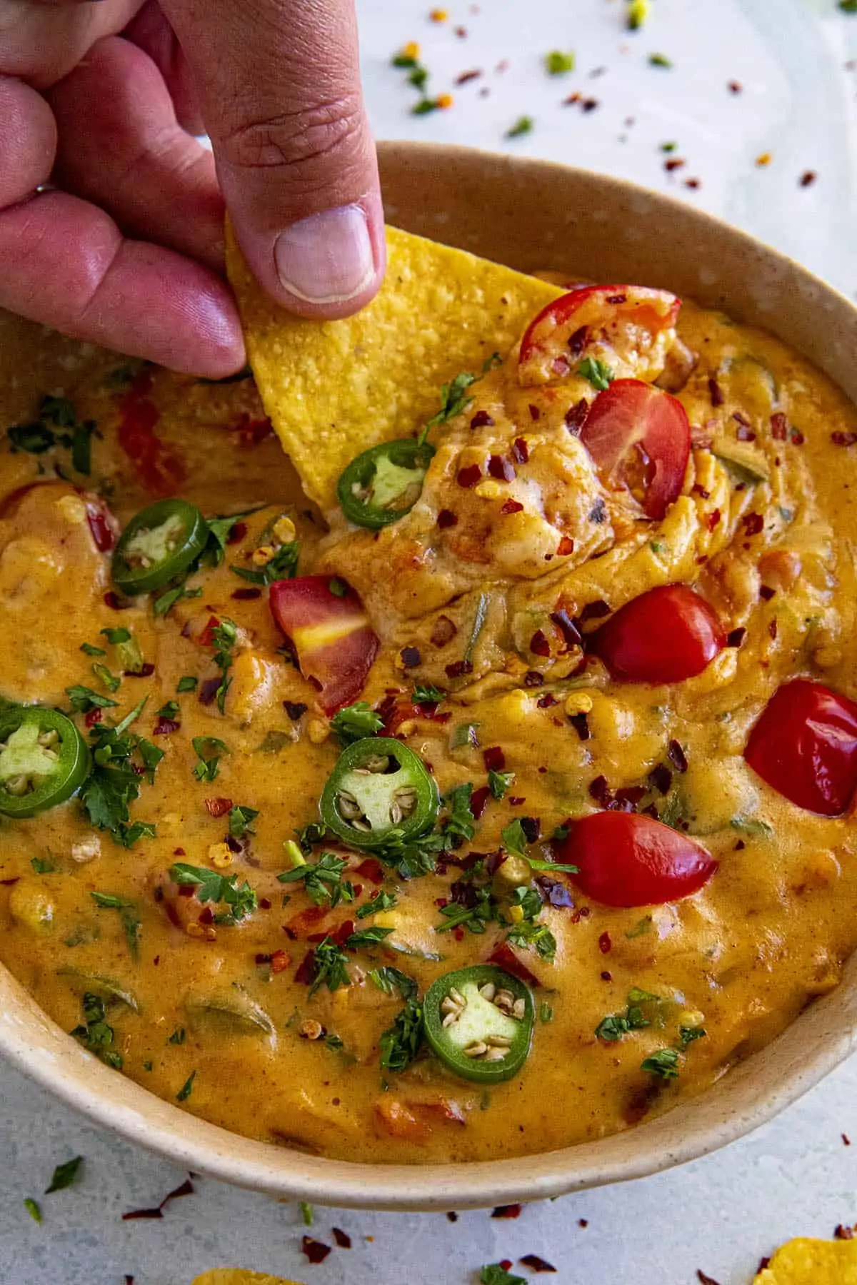 Dipping a chip into a bowl of hot queso dip.