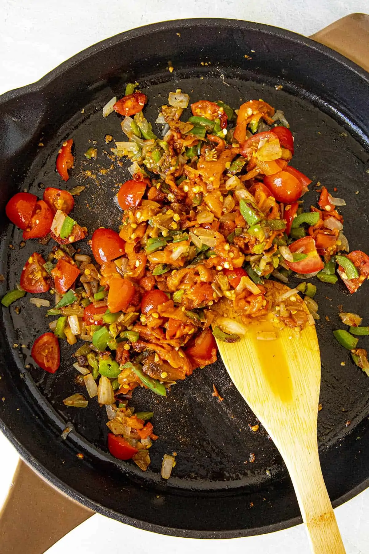 Cooking peppers, onions and tomatoes in a hot pan.