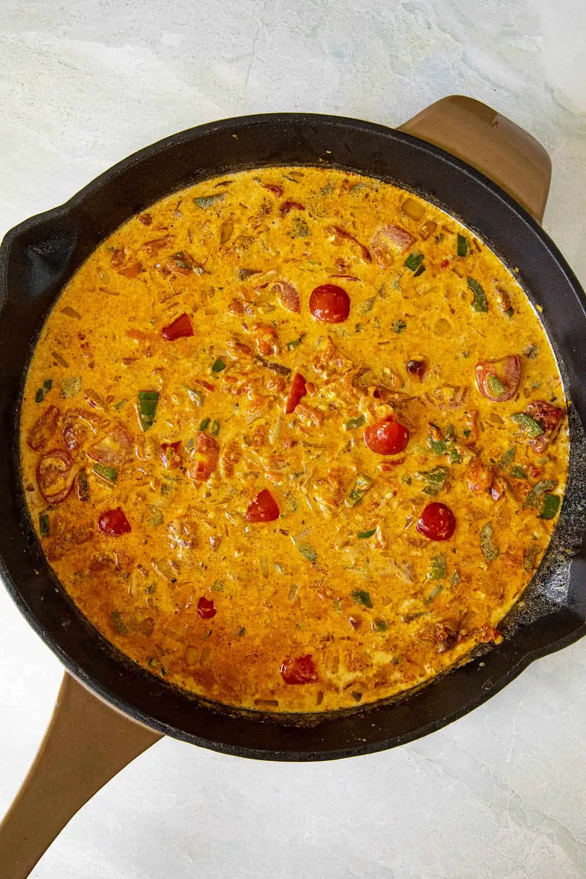 Simmering vegetables and milk to make queso dip.